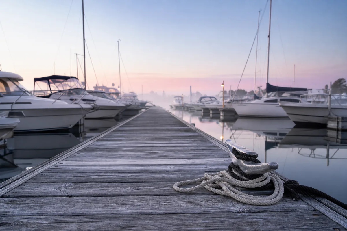 Ponton de port de plaisance au lever du jour, bateaux à moteur amarrés en enfilade