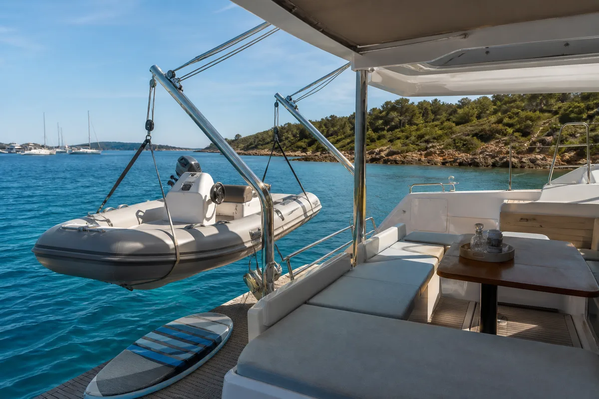 Le cockpit arrière d&rsquo;un catamaran de croisière au mouillage avec annexe sur bossoirs et paddle rangé sur le trampoline